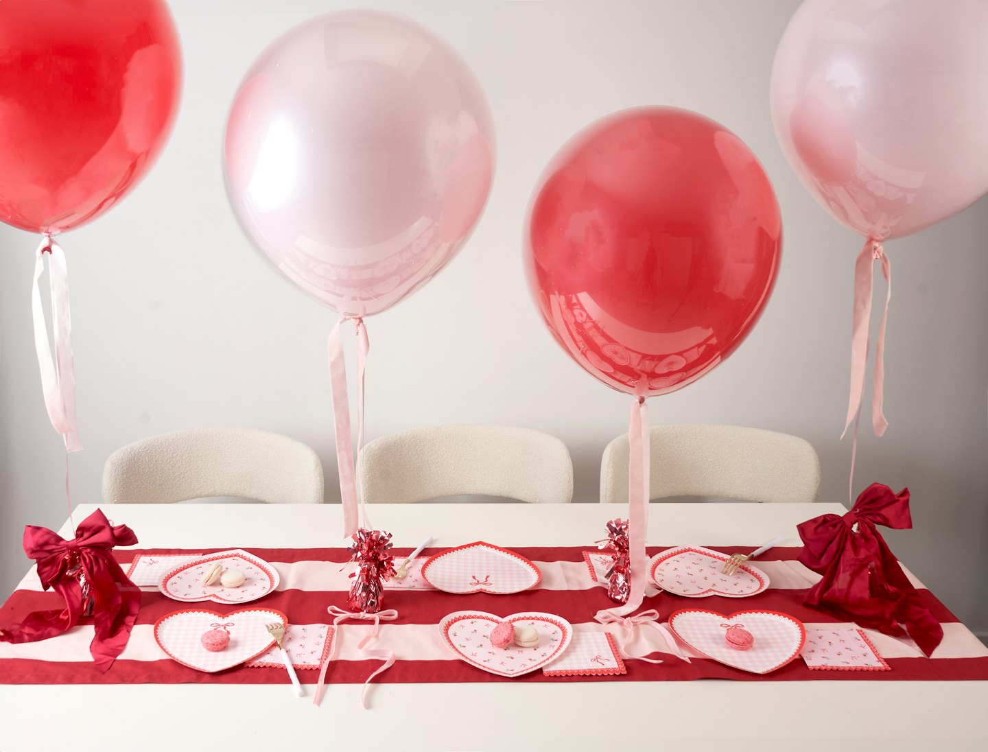 Rote und pinke Luftballons über einem Esstisch
